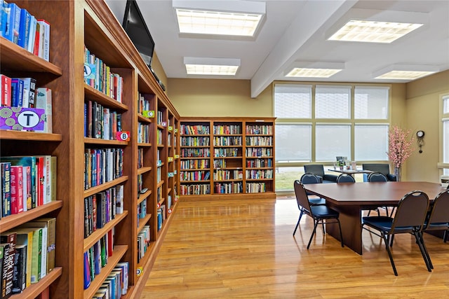 interior space featuring wall of books, light wood finished floors, and floor to ceiling windows