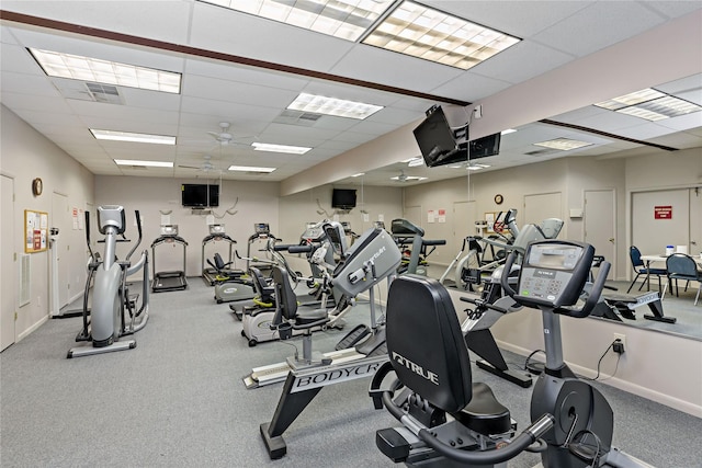 exercise room with a ceiling fan, baseboards, and a drop ceiling