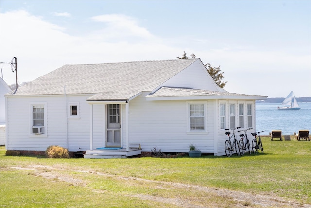 rear view of house with a lawn, roof with shingles, cooling unit, and a water view