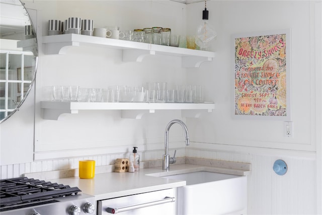 kitchen featuring dishwasher, light countertops, open shelves, and a sink