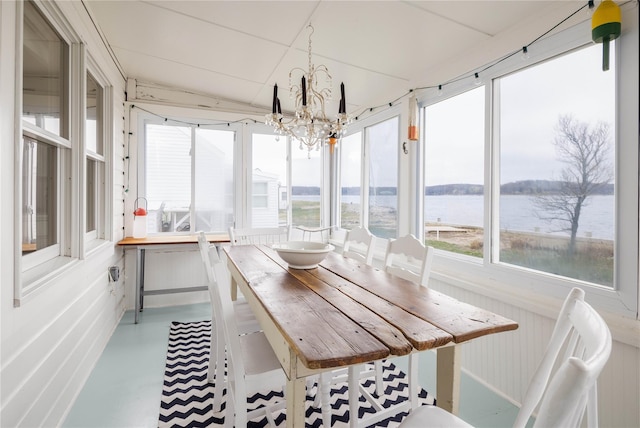 sunroom / solarium featuring concrete floors, an inviting chandelier, and a water view
