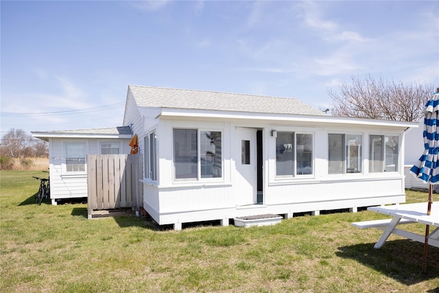 view of front of property featuring a front lawn and a shingled roof
