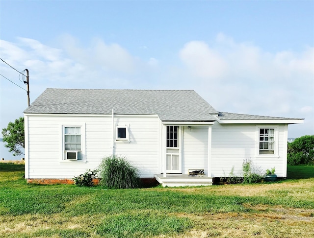 back of property featuring a shingled roof, cooling unit, and a yard