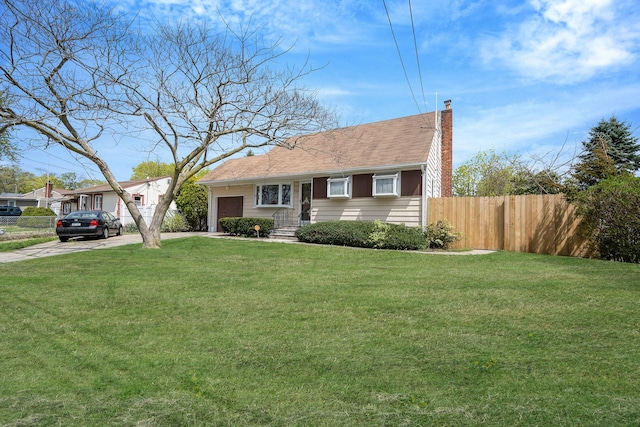 view of front facade with a chimney, fence, a front lawn, concrete driveway, and an attached garage