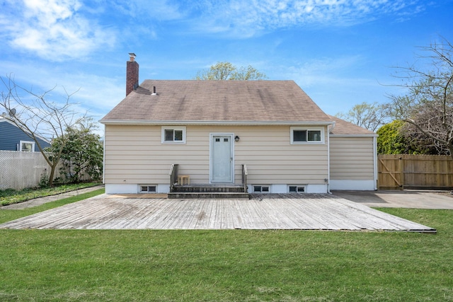 rear view of house with fence, a chimney, a lawn, and a deck