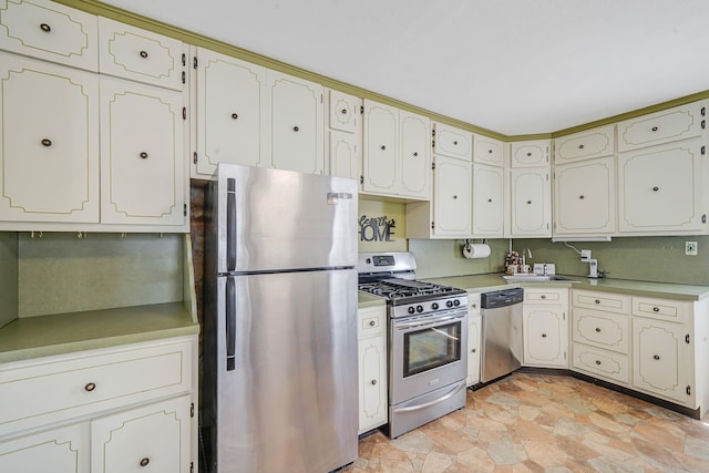 kitchen featuring a sink, appliances with stainless steel finishes, stone finish floor, and light countertops