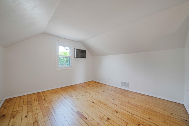 additional living space featuring baseboards, wood-type flooring, vaulted ceiling, and visible vents