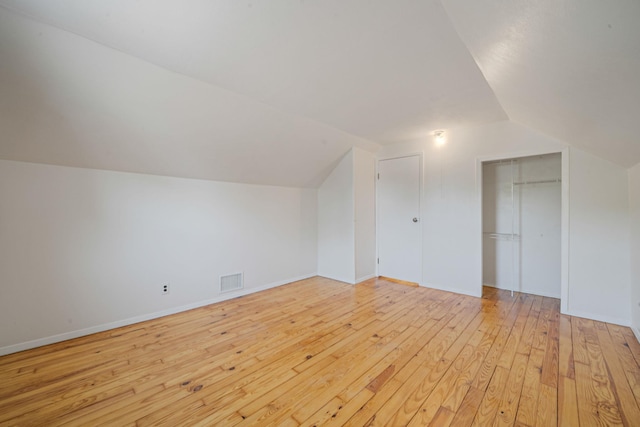 bonus room with baseboards, visible vents, light wood finished floors, and lofted ceiling