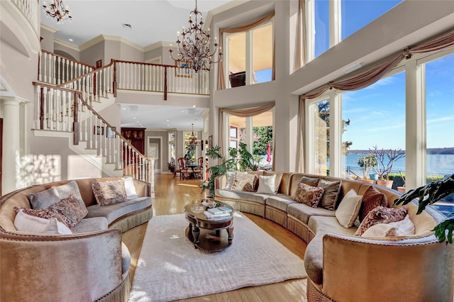 living room featuring ornamental molding, stairs, a towering ceiling, wood finished floors, and a notable chandelier