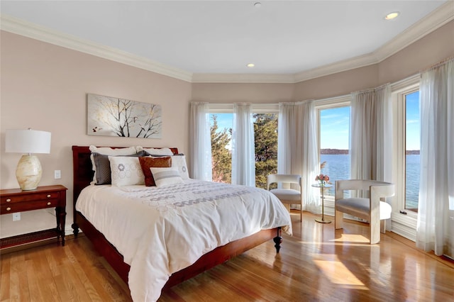 bedroom featuring crown molding, a water view, recessed lighting, and wood finished floors
