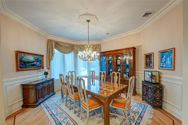 dining room featuring visible vents, ornamental molding, a wainscoted wall, and an inviting chandelier