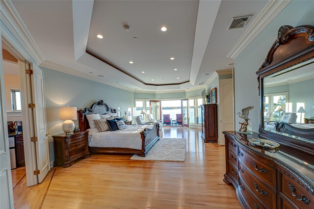 bedroom featuring visible vents, ornamental molding, recessed lighting, a tray ceiling, and light wood-style flooring