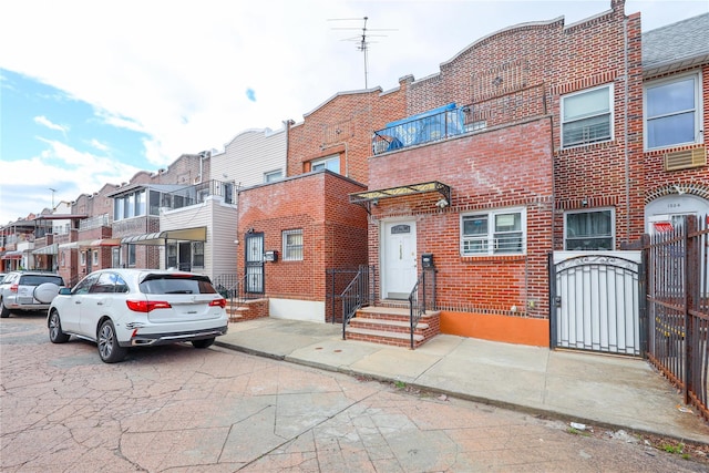view of property featuring brick siding, a gate, and a residential view