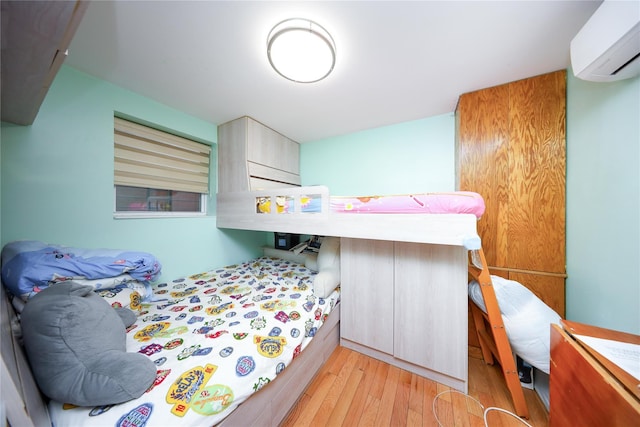 bedroom featuring a wall unit AC and light wood-style floors