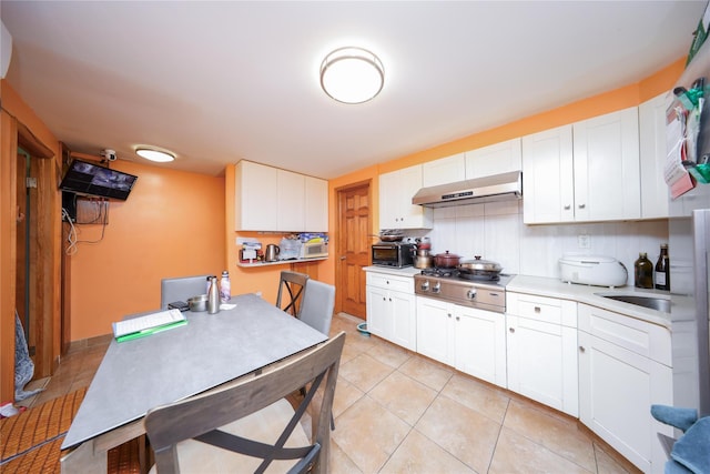 kitchen with under cabinet range hood, stainless steel gas stovetop, white cabinetry, and light countertops
