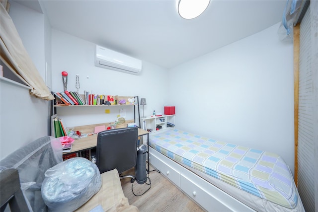 bedroom with a wall unit AC and wood finished floors