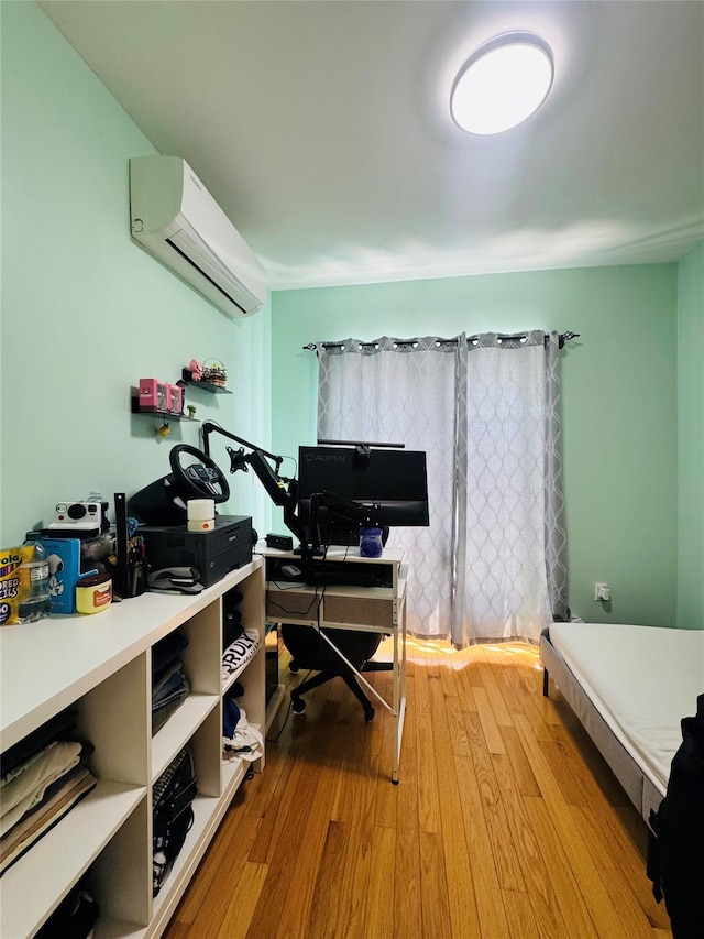bedroom with a wall mounted AC, wood finished floors, and a desk