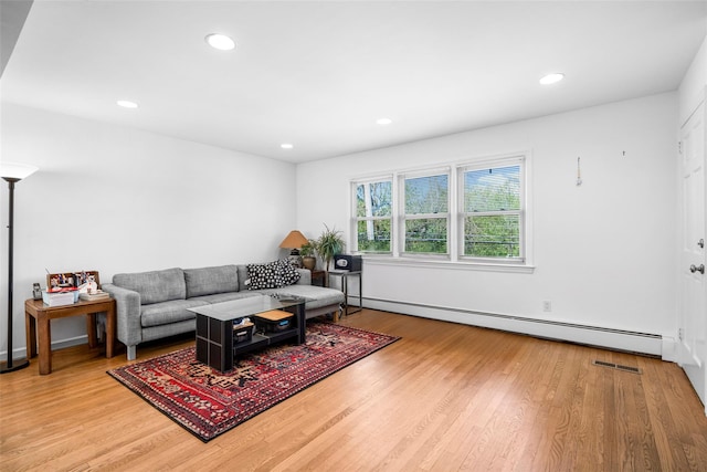 living room with a baseboard heating unit, light wood-style floors, and recessed lighting