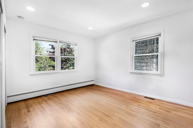 empty room featuring light wood finished floors, visible vents, baseboard heating, and recessed lighting