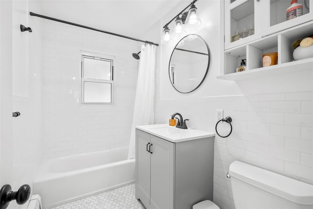 full bath featuring toilet, shower / bath combo with shower curtain, tile patterned floors, tile walls, and vanity
