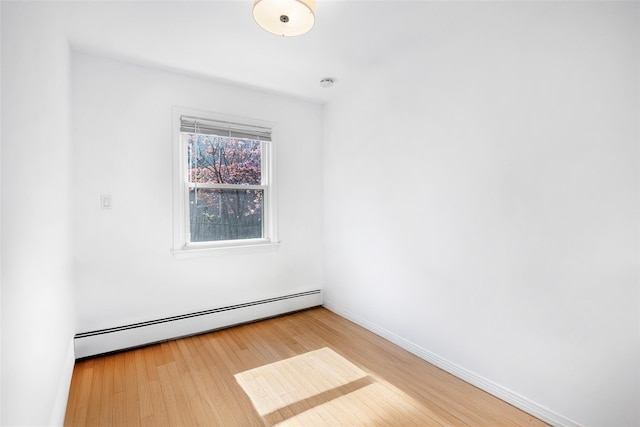 empty room featuring baseboards, wood finished floors, and a baseboard radiator
