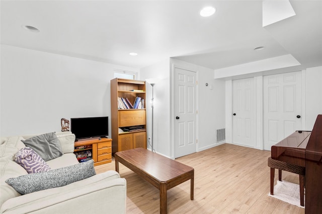living room featuring baseboards, light wood finished floors, recessed lighting, and visible vents