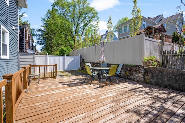 wooden deck with outdoor dining space and a fenced backyard