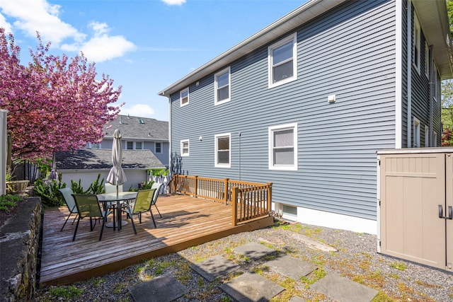 rear view of house with a deck, outdoor dining area, a shed, and an outbuilding