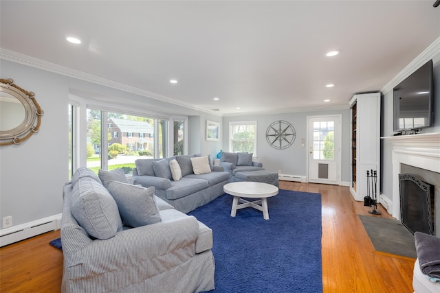 living room featuring a fireplace with flush hearth, a baseboard radiator, baseboard heating, ornamental molding, and wood finished floors