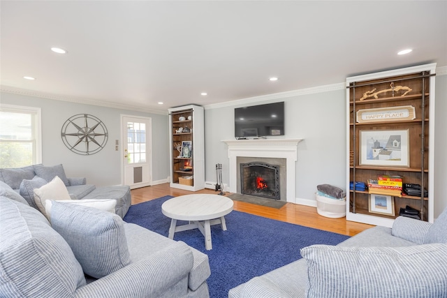 living area featuring wood finished floors, recessed lighting, ornamental molding, and a warm lit fireplace