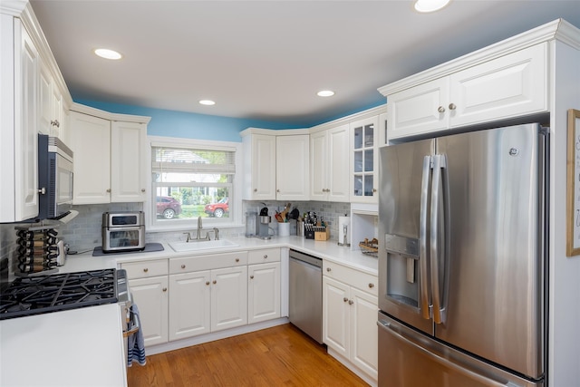 kitchen featuring white cabinets, stainless steel appliances, decorative backsplash, and a sink