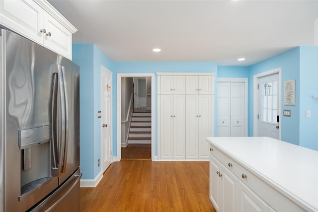 kitchen with recessed lighting, light wood-style floors, stainless steel fridge with ice dispenser, white cabinets, and baseboards