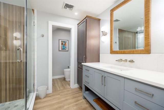 full bath featuring wood finished floors, visible vents, toilet, and a shower stall
