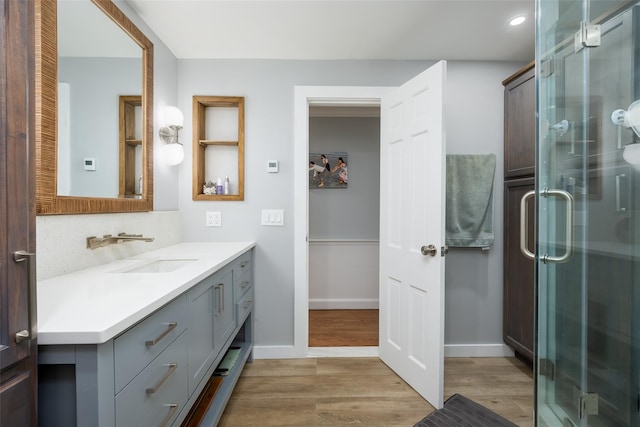 bathroom with baseboards, wood finished floors, a stall shower, and vanity