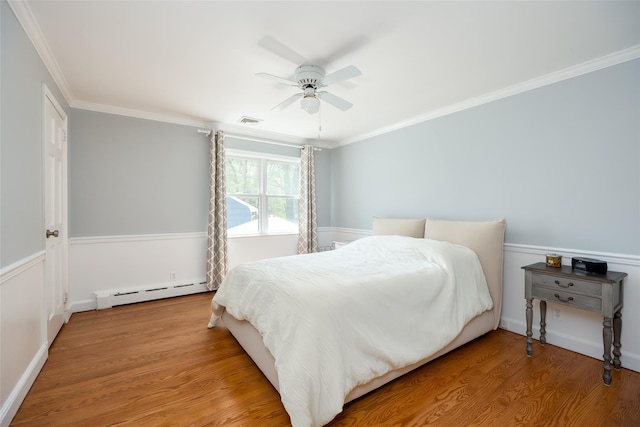 bedroom featuring wood finished floors, a baseboard radiator, ceiling fan, visible vents, and crown molding