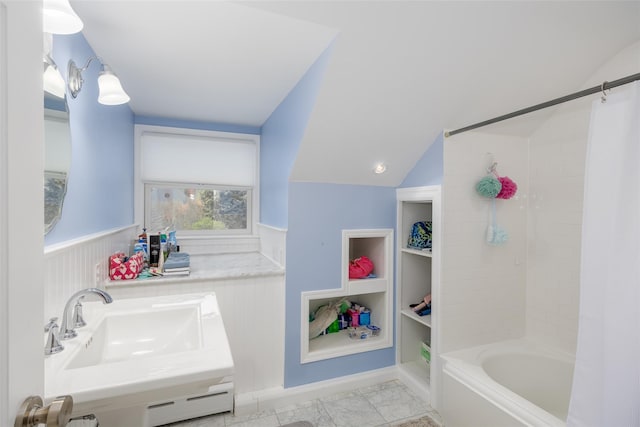 bathroom featuring a wainscoted wall, shower / tub combo with curtain, lofted ceiling, and marble finish floor