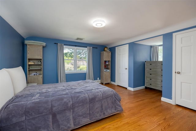 bedroom with wood finished floors, visible vents, and baseboards
