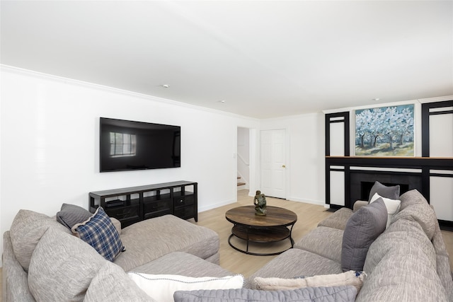 living room featuring baseboards, stairway, wood finished floors, and ornamental molding