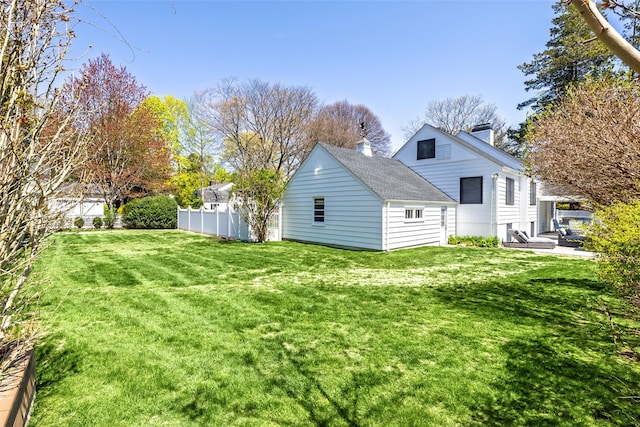 back of property featuring fence, a chimney, a lawn, and a shingled roof