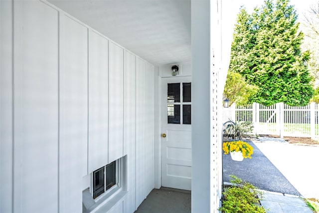 entrance to property featuring board and batten siding and fence