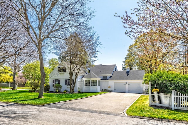 new england style home with a garage, fence, aphalt driveway, and a front lawn