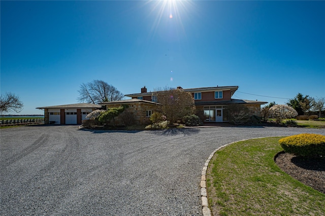 view of front of home with a garage, a chimney, stone siding, and aphalt driveway