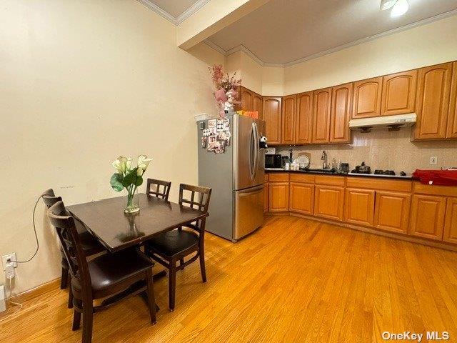 18-24 College Point Blvd, College Point, NY 11356 - kitchen featuring freestanding refrigerator, under cabinet range hood, ornamental molding, white gas stovetop, and light wood-type flooring