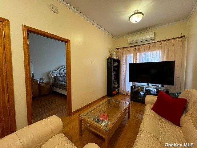 18-24 College Point Blvd, College Point, NY 11356 - living area with an AC wall unit, crown molding, and wood finished floors