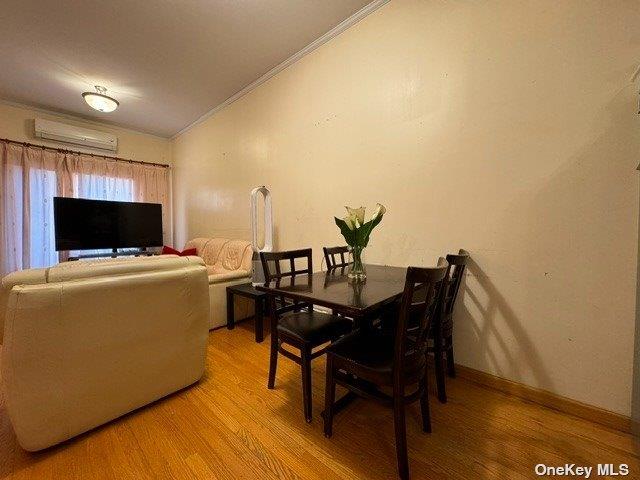 18-24 College Point Blvd, College Point, NY 11356 - dining room with vaulted ceiling, a wall mounted AC, ornamental molding, and light wood finished floors