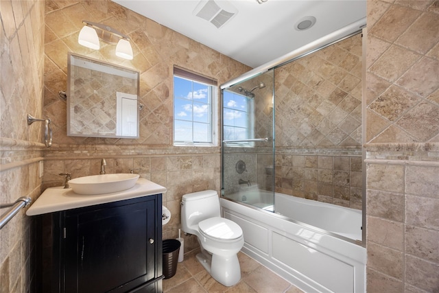 83 Central Ave, Amityville, NY 11701 - bathroom featuring bath / shower combo with glass door, visible vents, toilet, tile walls, and vanity