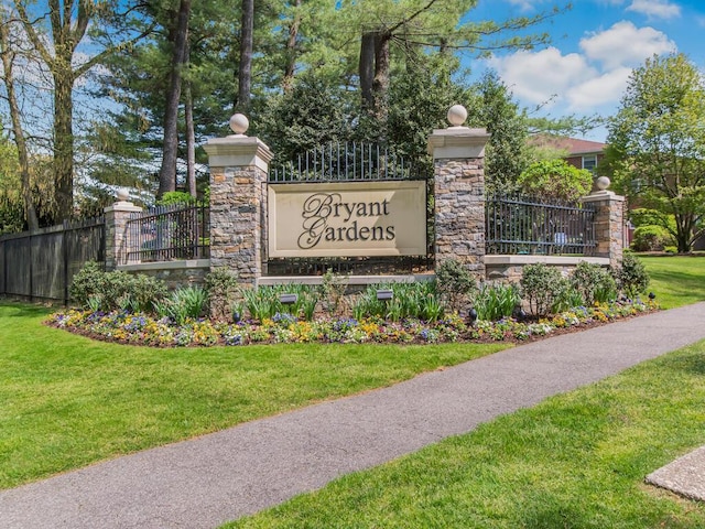 community / neighborhood sign featuring a yard and fence