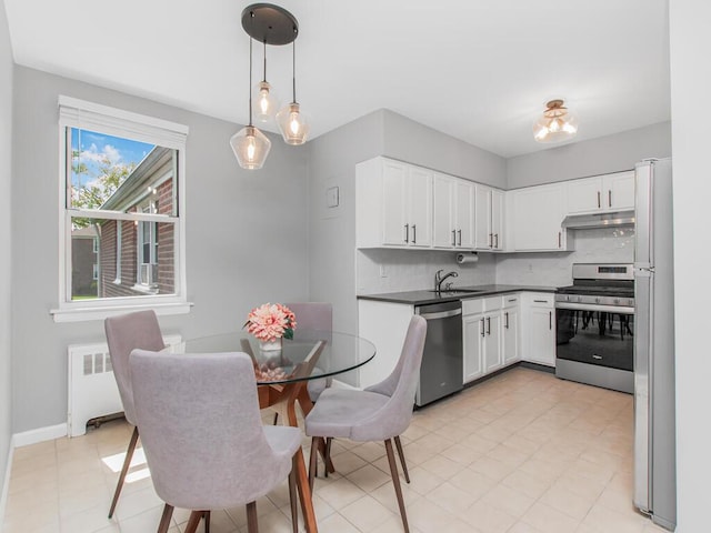 kitchen featuring dark countertops, white cabinetry, appliances with stainless steel finishes, tasteful backsplash, and radiator heating unit