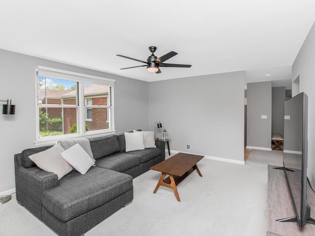 living room featuring a ceiling fan, baseboards, and light colored carpet
