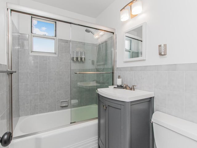 full bath with vanity, tile walls, toilet, and enclosed tub / shower combo